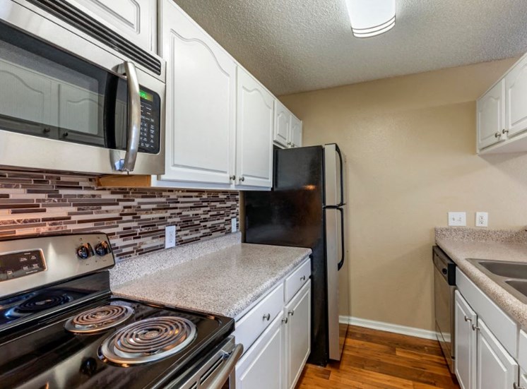 Kitchen with tiled backsplash, microwave, refrigerator, stove,  and hardwood style flooring